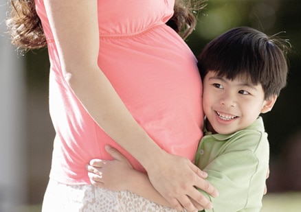 child with ear against mother's belly