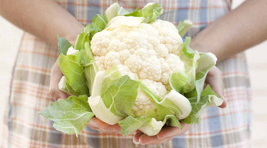 hand holding a head of cauliflower