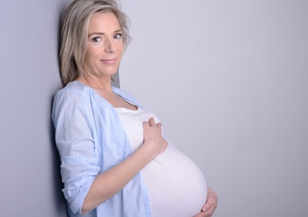 Pregnant older woman embracing her belly