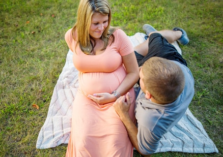 pregnant couple on blanket