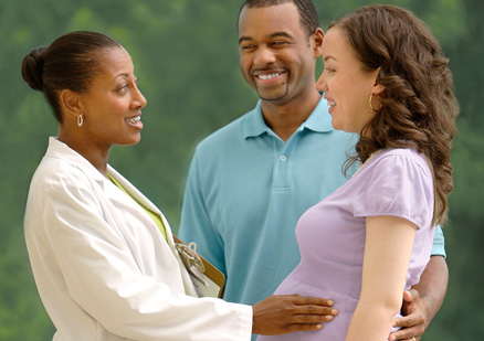 Pregnant couple talking with female doctor