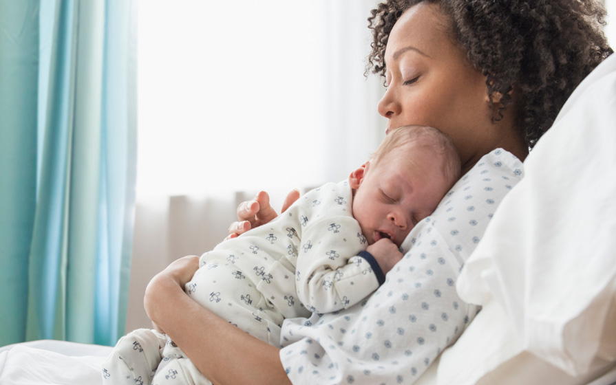 Sleeping mother and newborn baby in a hospital bed