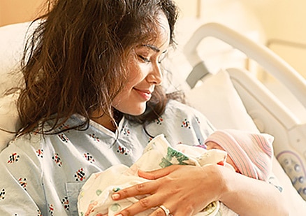 Smiling mother with newborn in arms