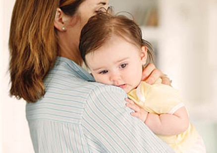 woman holding baby over shoulder