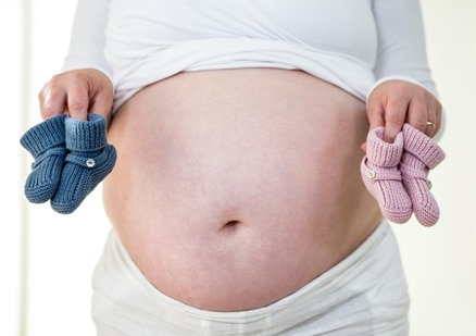 pregnant woman holding baby slippers