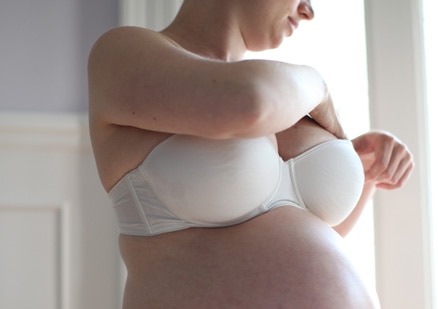 pregnant woman inspecting her breast