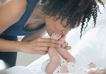 woman kissing baby's feet