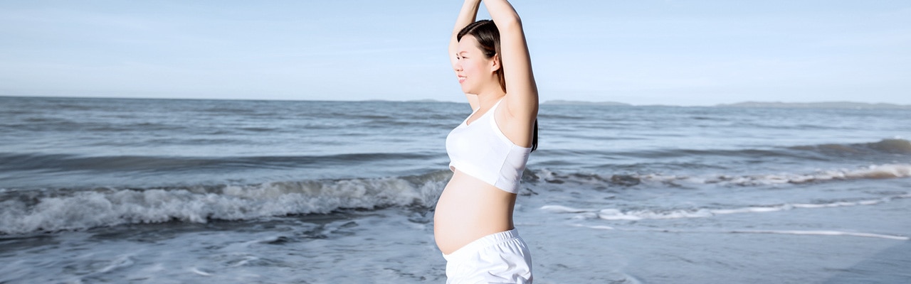 pregnant woman doing yoga on the beach