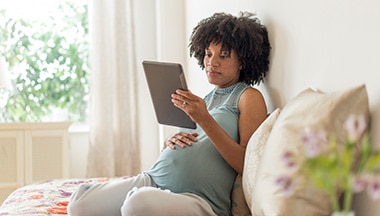 Pregnant woman holding a tablet.