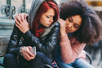 A person putting their hands on another person’s shoulders for comfort