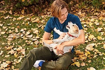 A teen holding a dog outside in the grass