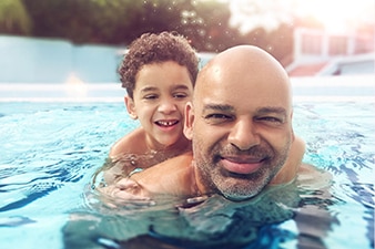 Child hanging on parent's back in a pool