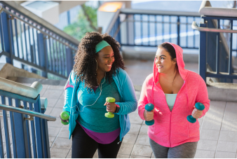 2 smiling friends exercising on an outdoor staircase