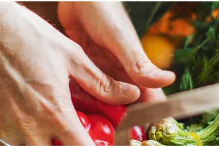 A woman holds a bowl of freshly chopped vegetables