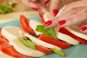 Person placing tomato and cheese on plate