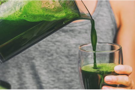 Person pours green juice into a cup