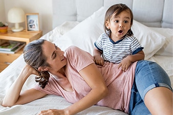 Parent and toddler playing on a bed