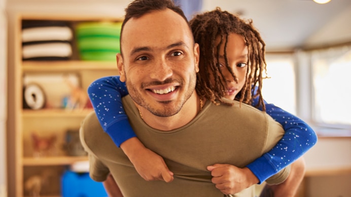 Smiling parent giving their child a piggyback ride