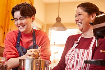 Smiling teenager and mom baking together in the kitchen