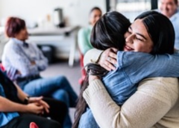 two people hugging at a community group meeting