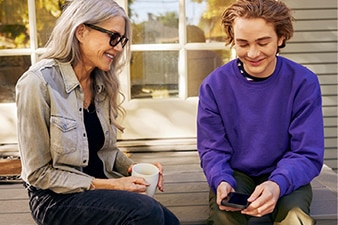 Teenager holding their phone while talking to an adult