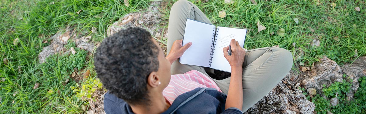 Woman sitting outside writing in journal Woman sitting outside writing in journal