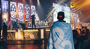 Young adult in backwards hat watches stage at gaming convention