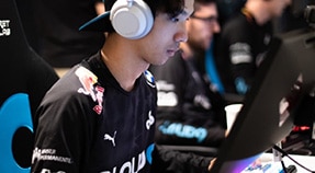 Young adult with large headphones sits at laptop