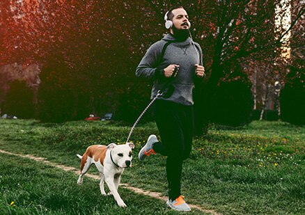 Young man running in park with his dog