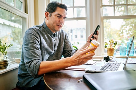 Person holding prescription bottle and phone