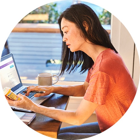 Person at computer with prescription bottle