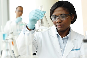 Kaiser Permanente scientist examining a beaker in a lab