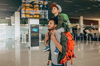 Parent holding a small child on their shoulders at an airport