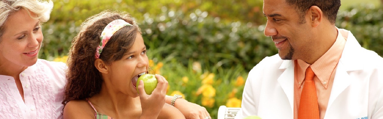 child-eats-apple-looking-at-doctor