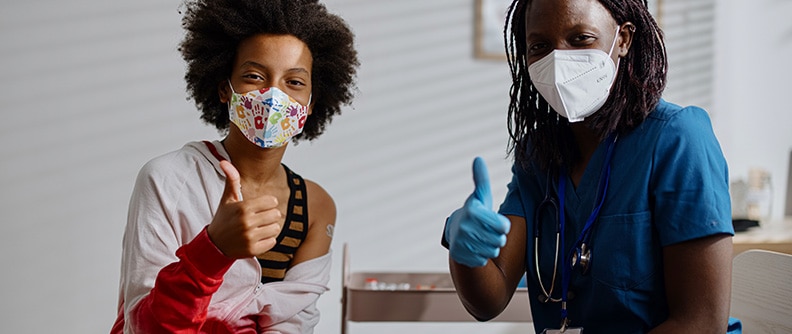 masked nurse and teen give thumbs up