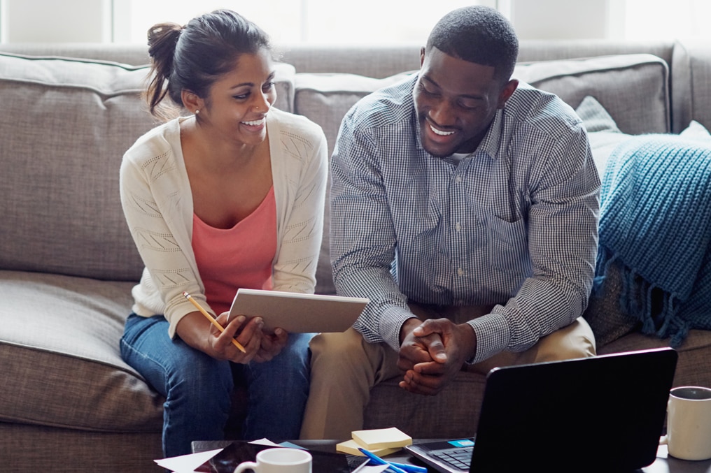Couple smiling sitting on couch reviewing notes image