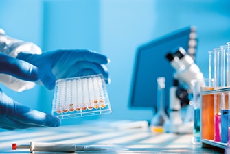 Gloved hands holding vials in a lab