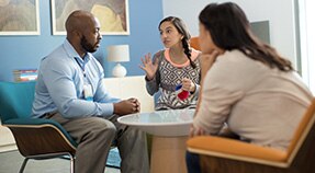 Teen and two adults have conversation around table