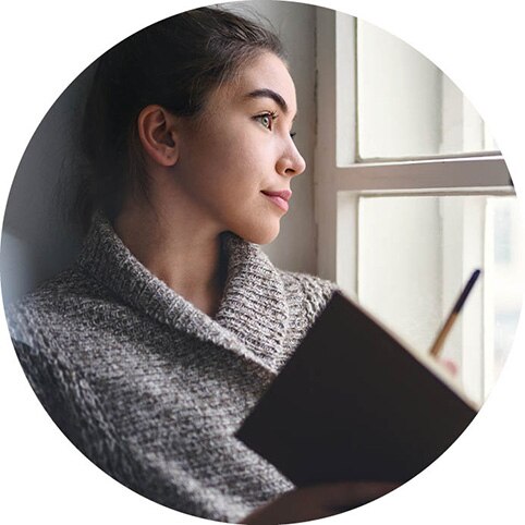 Person journaling beside a window