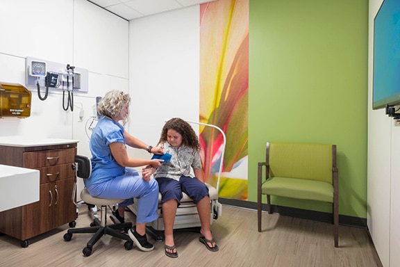 A care provider holds a bottle of pills to show to her patients