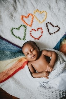 Baby sleeping on a blanket with rainbow hearts 