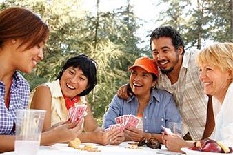 Smiling group of friends playing cards outdoors