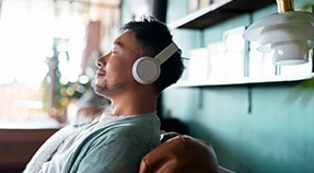 Adult in headphones leans back with eyes closed