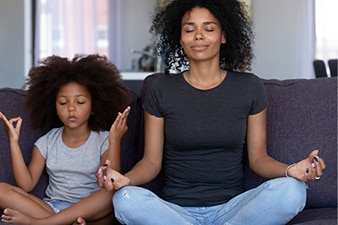 Adult and child doing a meditation pose