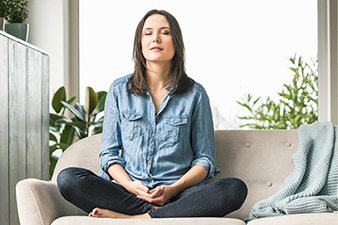 Person sitting cross-legged and meditating on a couch