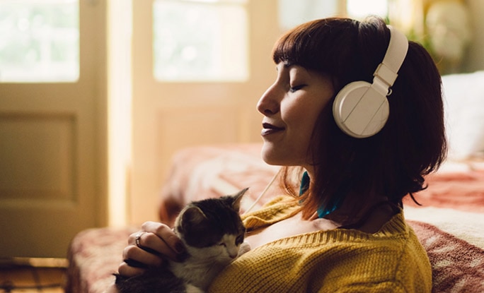 Happy person holding kitten and listening to headphones