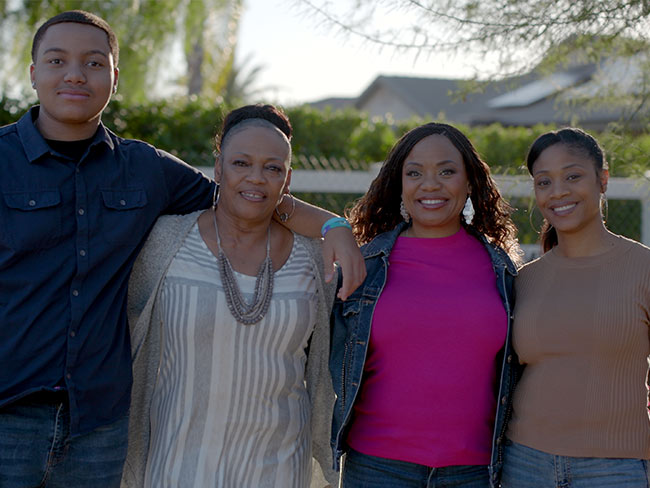 Kaiser Permanente member Tasha Champion standing outdoors with her son, her mother, and her sister, Tish Smith.