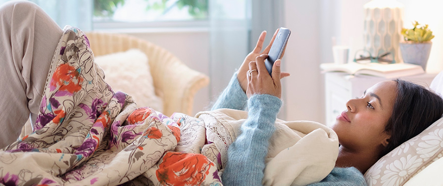 Person in bed looking at smart phone