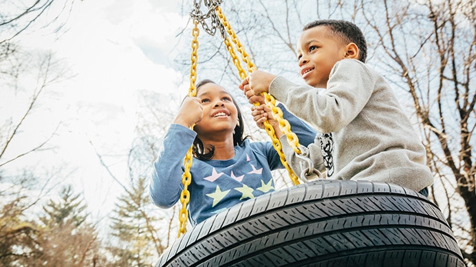 two children playing on tire swing