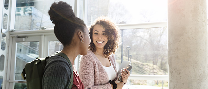 Two people walking and chatting near a window